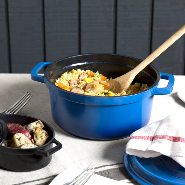 A cobalt blue GET Heiss round Dutch oven with food and a wooden spoon in it.