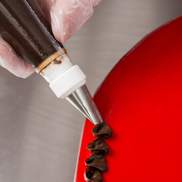 A hand using an Ateco wavy petal piping tip on a red plate.