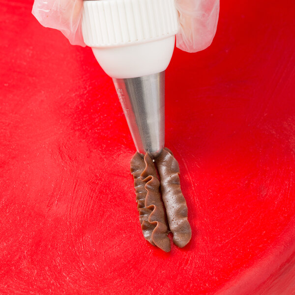 A person uses an Ateco drop flower piping tip in a pastry bag to make chocolate covered pretzels.