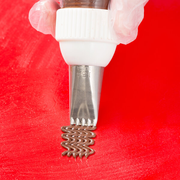 A pastry bag with a brown liquid on the tip using an Ateco 134 5-hole piping tip.
