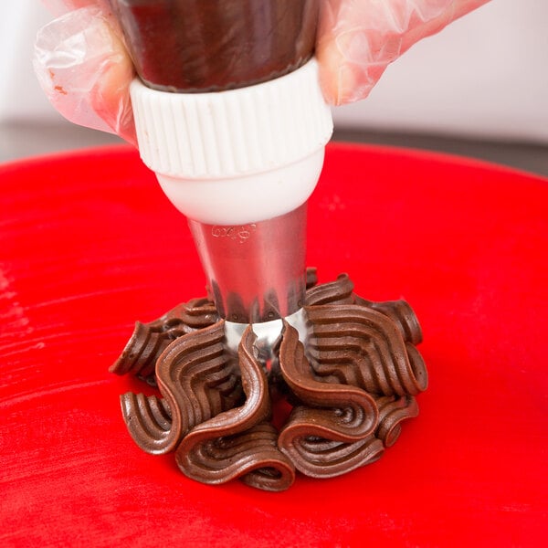 A person using an Ateco Russian ball tip piping tip to make chocolate swirls with a pastry bag.