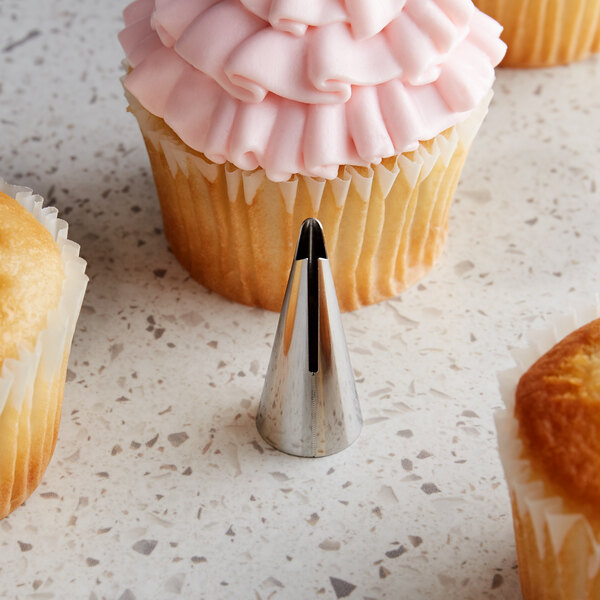 A cupcake with pink frosting and a ruffled cone on top.