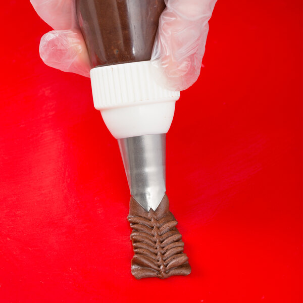A hand using an Ateco leaf piping tip on a pastry bag.
