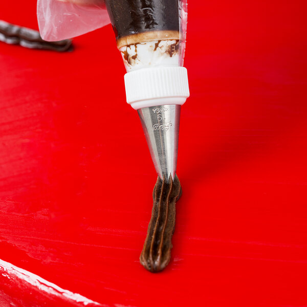 A close-up of an Ateco Open Star Piping Tip on a pastry bag over a red surface.
