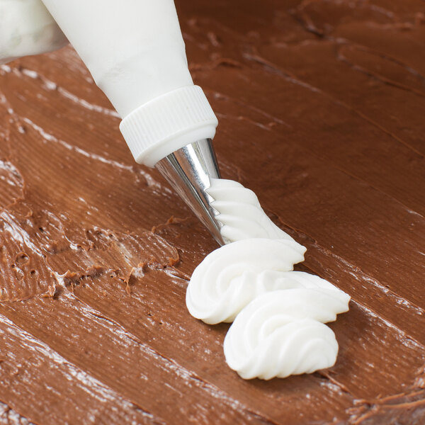 White frosting piped with an Ateco ruffle piping tip onto a brown surface.