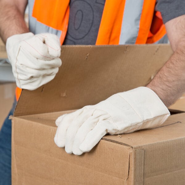 A man wearing Cordova Standard Weight Cotton work gloves opening a box.