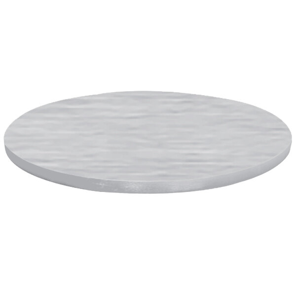 A close-up of a Tablecraft round translucent clear brushed aluminum table cover on a round table with a white surface.