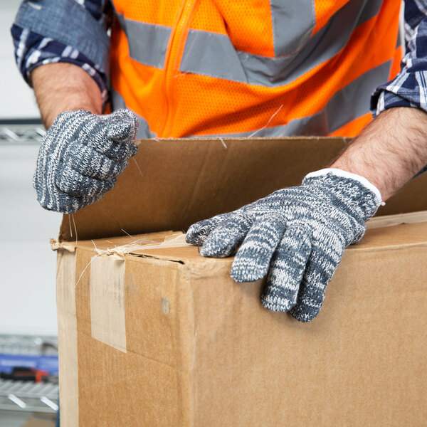A person wearing Cordova extra heavy weight work gloves opening a box.