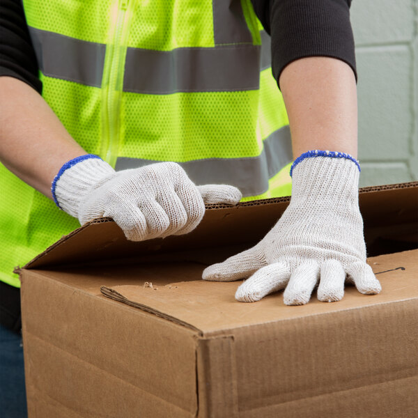 A person wearing Cordova work gloves opening a box.