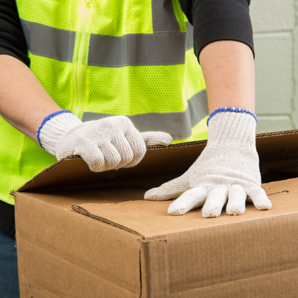 A person wearing Cordova natural polyester/cotton work gloves opening a box.