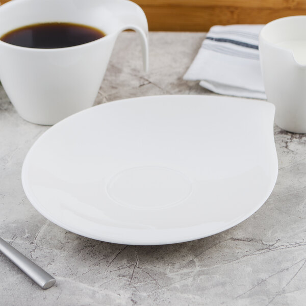 A white Villeroy & Boch porcelain saucer on a table with a cup of coffee.