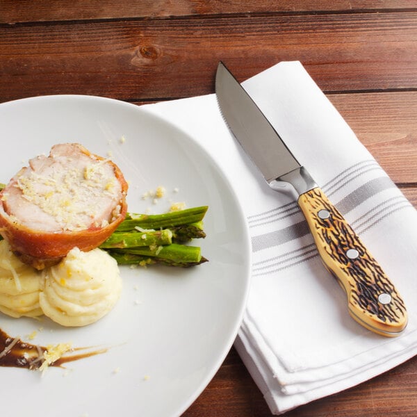 A plate of food with a Walco steak knife on a napkin.