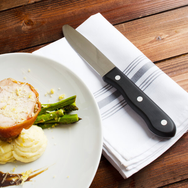 A plate of food with a Walco stainless steel steak knife on it.