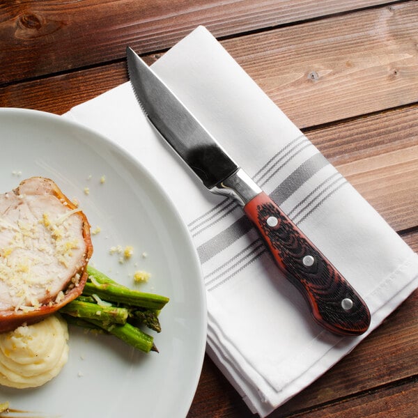 A plate of food with a Walco stainless steel steak knife and napkin.