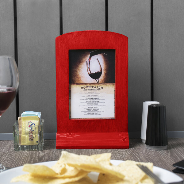 A red wooden framed Menu Solutions table tent on a table with a menu inside.
