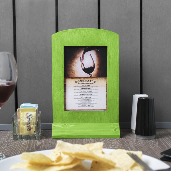 A lime wood menu tent with an angled base holding a menu on a table with chips.