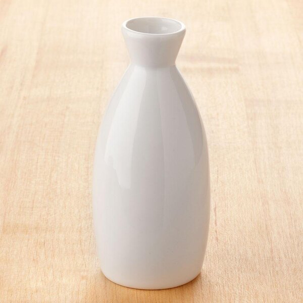 A white ceramic Town sake bottle with a white lid on a wood surface.