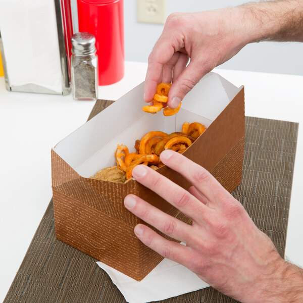 A hand putting food into a Hearthstone take-out box.