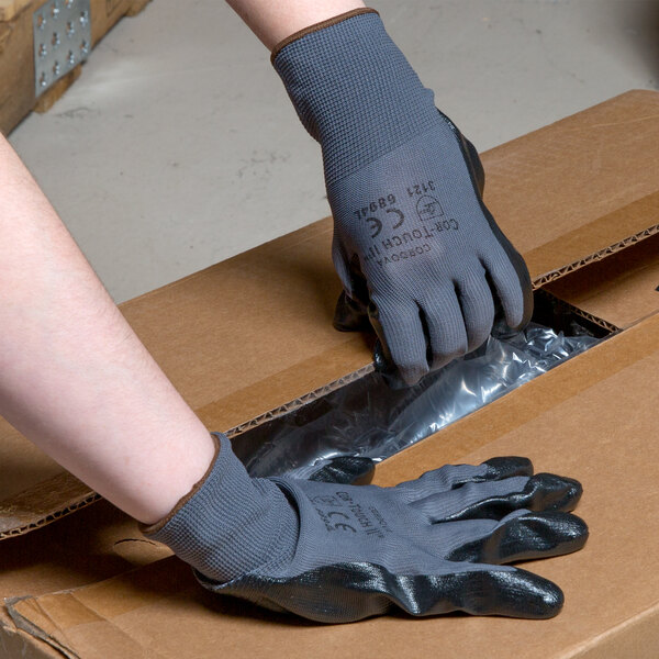 A person wearing Cordova Cor-Touch II gloves while putting on a box.