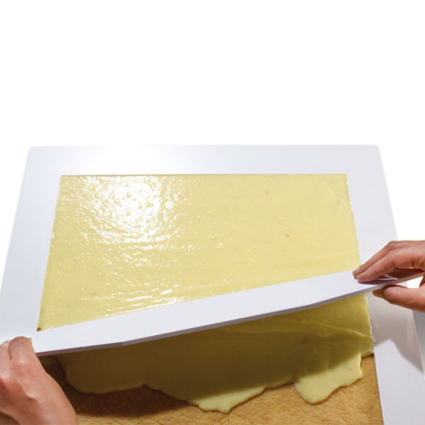 A person using a white plastic knife to cut a rectangular cake