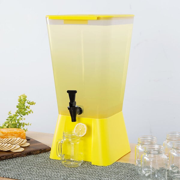 A yellow Choice beverage dispenser with a glass on a table.