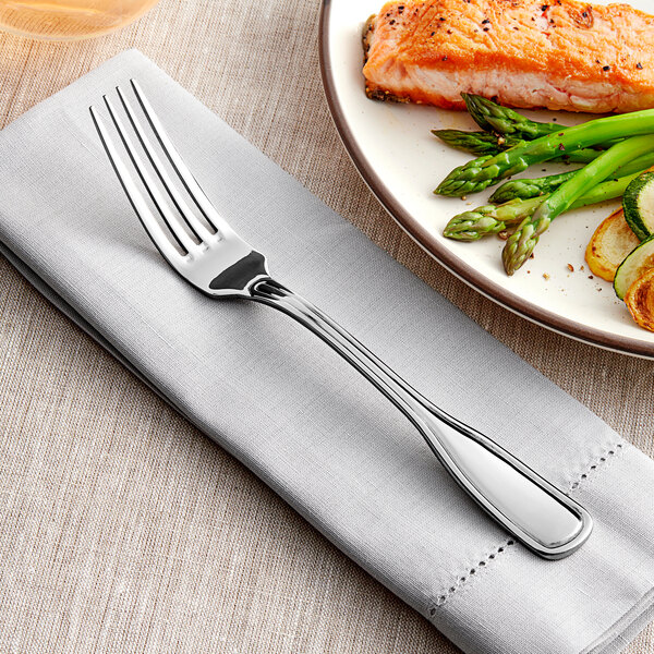 An Acopa stainless steel table fork on a plate with food.