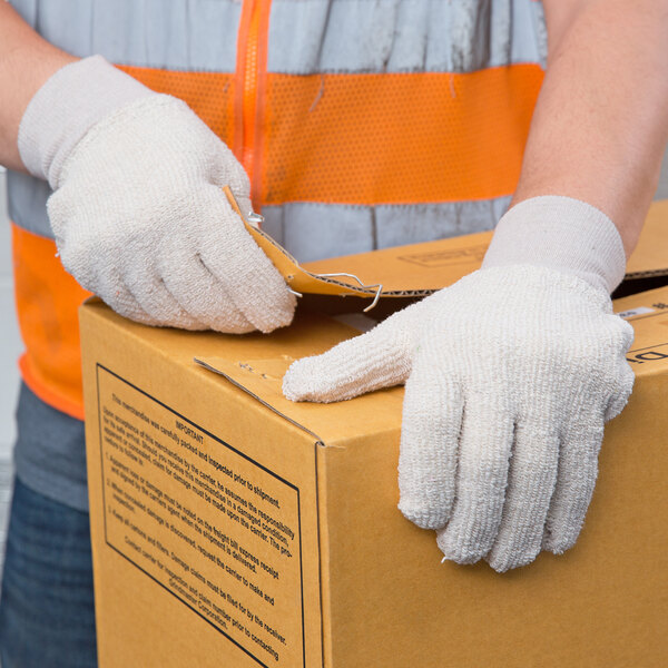 A person wearing Cordova loop-out terry work gloves opening a box.