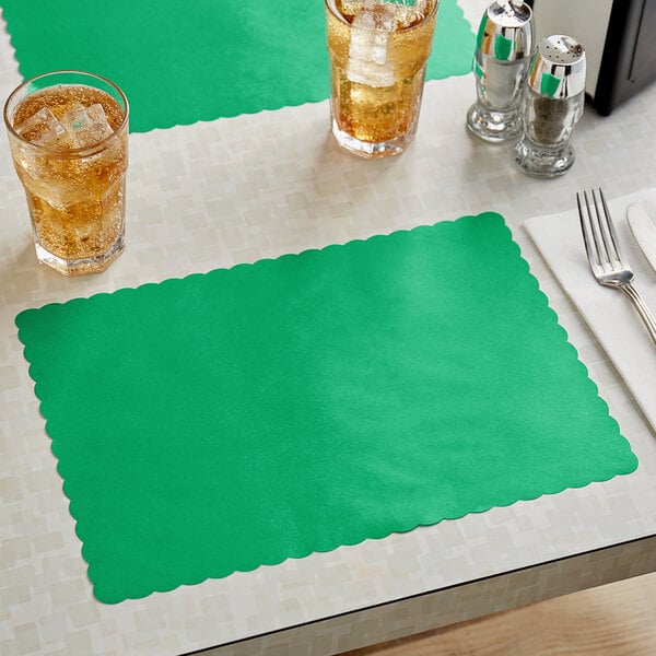 A table set with a green scalloped paper placemat and two glasses of ice tea.