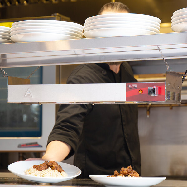 An Avantco strip warmer mounted over a counter with a plate of food on it.