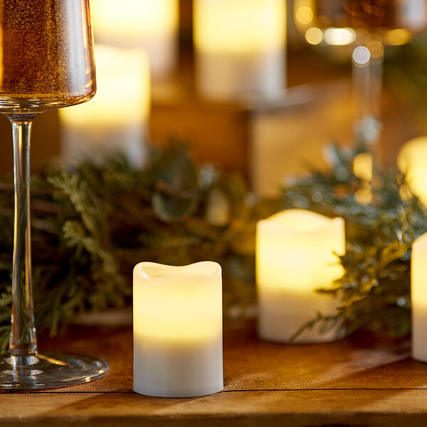 Sterno flameless candles lit on a table with wine glasses.