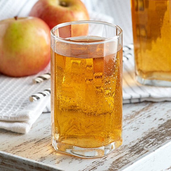 A close up of a glass of Narvon apple juice with a straw.