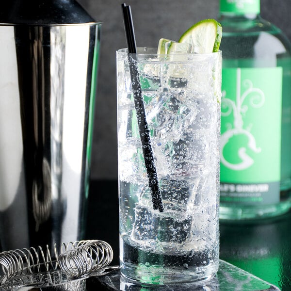 A glass of Narvon Tonic with ice and a lime wedge with a straw in it.