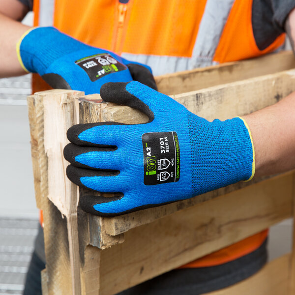 A person wearing Cordova Sapphire Blue gloves holding a piece of wood.