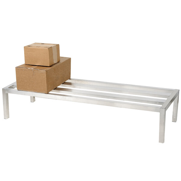 An aluminum E-channel dunnage rack with a stack of brown boxes on it.