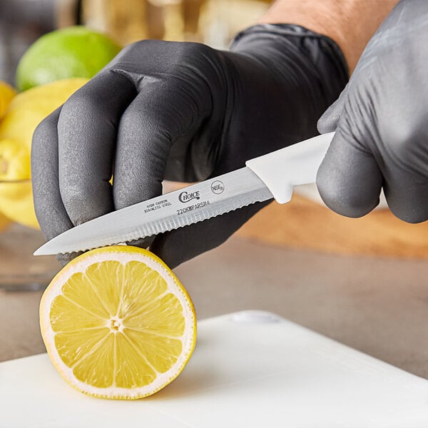 A person cutting a lemon with a Choice serrated edge paring knife.