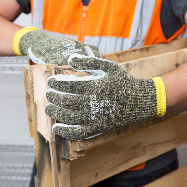 A man wearing Cordova Power-Cor Max Camo work gloves holding a piece of wood.