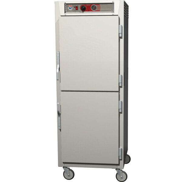 A stainless steel Metro C5 reach-in holding cabinet on wheels with two doors, one solid and one clear.