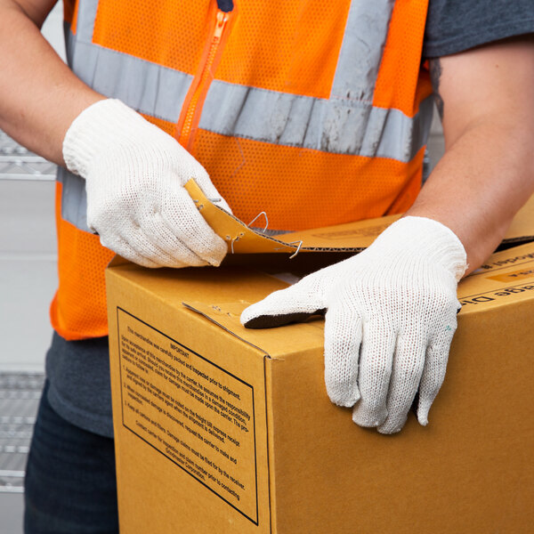 A person wearing Cordova Natural polyester/cotton work gloves with black PVC palm coating and holding a box.