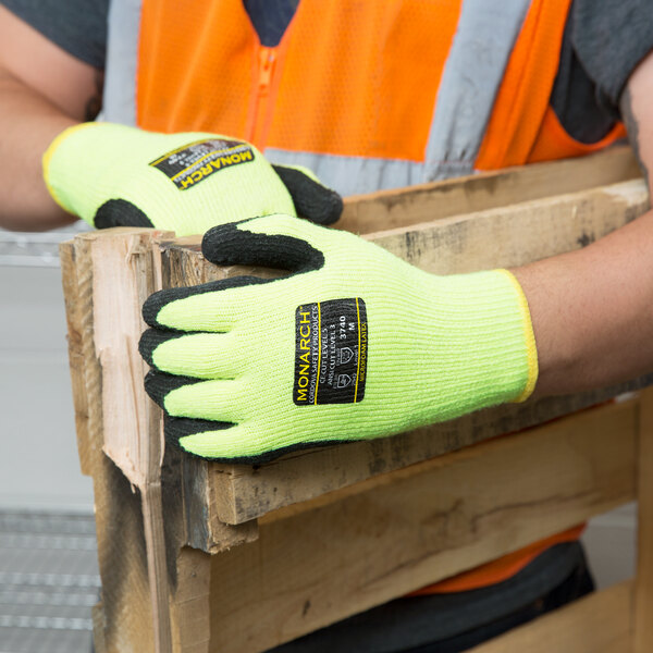 A person wearing Cordova Monarch heavy duty work gloves and holding a piece of wood.