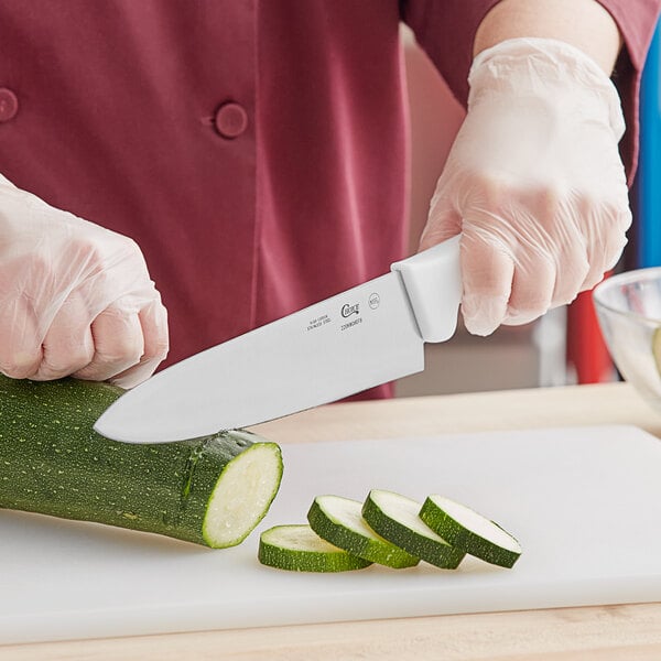 A person using a Choice 8" Chef Knife to cut a zucchini.