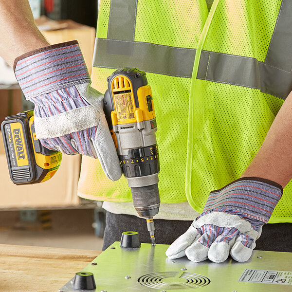 A person wearing Cordova warehouse gloves with a yellow and black tool using a drill.