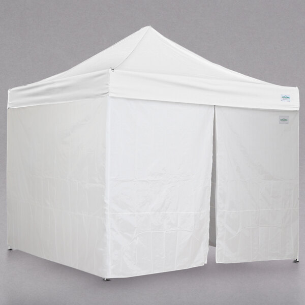 A white Caravan Canopy instant canopy with two doors and two windows.