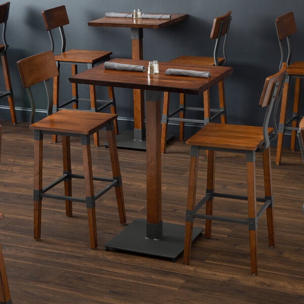 A Lancaster Table & Seating solid wood live edge bar height table with wooden stools at a restaurant.