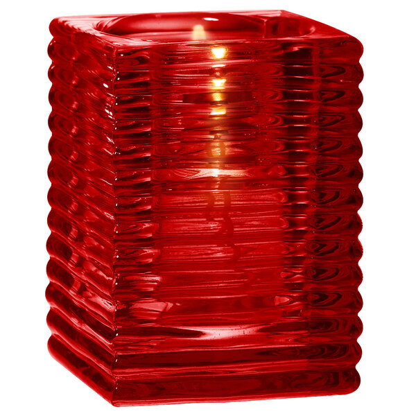 A Sterno red glass square candle holder with a lit candle.