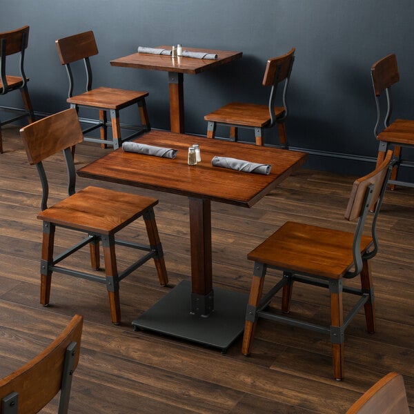 A Lancaster Table & Seating wooden live edge dining table and chairs in a restaurant dining area.