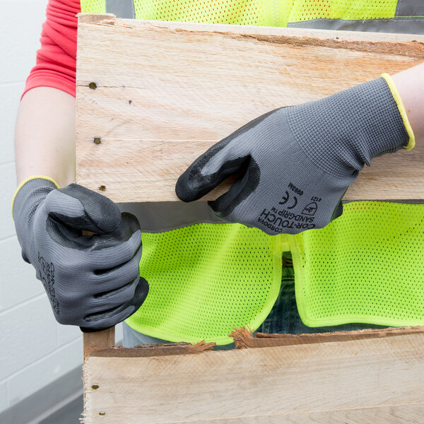 A person wearing Cordova Cor-Touch safety gloves holding a piece of wood.