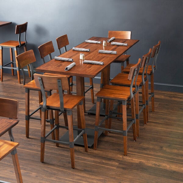 A Lancaster Table & Seating bar height table with wooden chairs in a restaurant dining area.