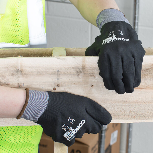 A person wearing Cordova Conquest Xtreme gloves holding a piece of wood.