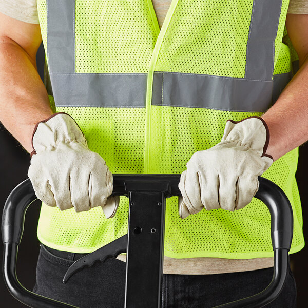 A man wearing Cordova Select grain pigskin leather driver's gloves and a safety vest holding a hand truck.