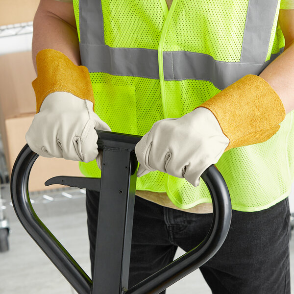 A man wearing Cordova leather welder's gloves and a safety vest holding a metal frame.